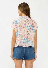 [Color: Ivory/Orange] A back facing image of a brunette model wearing an ivory and orange floral boho top with short sleeves, a v neckline, and a tie front detail.