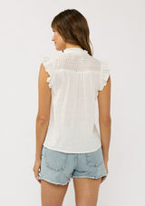 [Color: Off White] A back facing image of a brunette model wearing a cotton white top with a button front, an eyelet yoke, and flutter cap sleeves. Airy and relaxed for the spring season.