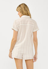 [Color: Sand/Off White] A back facing image of a blonde model wearing a cotton striped shirt with a puckered texture, collar neck, button front, and short sleeves. Styled with matching shorts. 