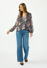 [Color: Grey/Dusty Rose] A front facing image of a brunette model wearing a relaxed peplum top with a floral print, clipped lurex, and a v neckline with tie detail. 