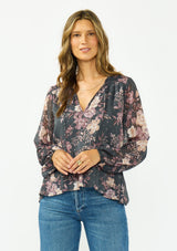 [Color: Grey/Dusty Rose] A front facing image of a brunette model wearing a relaxed peplum top with a floral print, clipped lurex, and a v neckline with tie detail. 