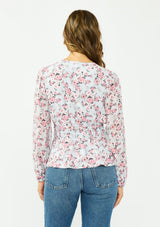 [Color: Grey/Dusty Rose] A back facing image of a brunette model wearing a floral print peplum top with a split neckline and a shirred elastic waist. 