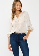 [Color: White/Sand] A front facing image of a brunette model wearing a white bohemian embroidered blouse with a button front. 