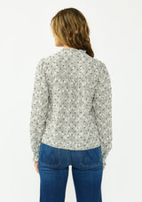[Color: Black] A back facing image of a brunette model wearing a black and white checkered pattern blouse with embroidered details and a button front. 
