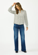 [Color: Black] A front facing image of a brunette model wearing a black and white checkered pattern blouse with embroidered details and a button front. Styled with a dark wash denim with black loafers. 