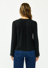 [Color: Black] A back facing image of a brunette model wearing a black lace long sleeve top with a scoop neckline and button front. 