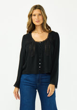 [Color: Black] A front facing image of a brunette model wearing a black lace long sleeve top with a scoop neckline and button front. 