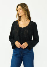 [Color: Black] A front facing image of a brunette model wearing a black lace long sleeve top with a scoop neckline and button front. 
