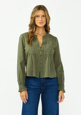 [Color: Olive] A front facing image of a brunette model wearing an olive green embroidered blouse with a button front and a button cuff closure with ruffle trim. Paired with a dark wash denim.