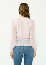 [Color: Lilac] A back facing image of a brunette model wearing a sheer lilac top with a front lace accent, button front, long sleeves, and a tie front waist detail. 