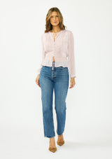[Color: Lilac] A front facing image of a brunette model wearing a sheer lilac top with a front lace accent, button front, long sleeves, and a tie front waist detail. 