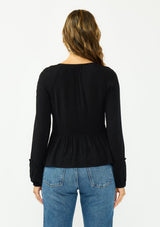 [Color: Black] A back facing image of a brunette model wearing a black long sleeve top with a shirred bust area. 