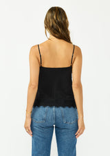 [Color: Black] A back facing image image of a brunette model wearing a black lace cami with spaghetti straps. Styled with dark wash denim. 