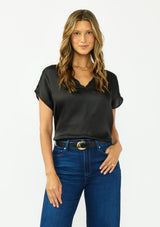 [Color: Black] A front facing image of a brunette model wearing a black satin top with an embroidered trim and short dolman sleeves. 