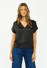 [Color: Black] A front facing image of a brunette model wearing a black satin top with an embroidered trim and short dolman sleeves. 