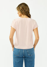 [Color: Shell] A back facing image of a brunette model wearing a pink lace trim top with short dolman sleeves and a button front. 