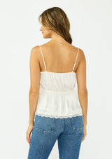 [Color: Ivory] A back facing image of a brunette model wearing a poly satin lace trim top with  a button front, adjustable spaghetti straps, and a drawstring waist with tie detail. Paired with a classic blue denim. 
