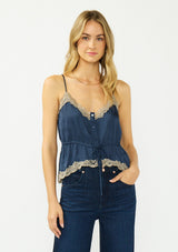 [Color: Navy/Taupe] A front facing image of a blonde model wearing a navy blue poly satin lace trim top with  a button front, adjustable spaghetti straps, and a drawstring waist with tie detail. Paired with a classic dark wash denim.