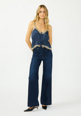 [Color: Navy/Taupe] A front facing image of a blonde model wearing a navy blue poly satin lace trim top with  a button front, adjustable spaghetti straps, and a drawstring waist with tie detail. Paired with a classic dark wash denim.