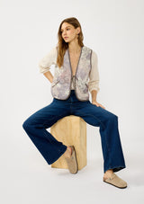 [Color: Natural/Lavender] A front facing image of a blonde model wearing a cozy fall floral sherpa vest with a tie front detail and side pockets. Perfect for layering any boho look. 