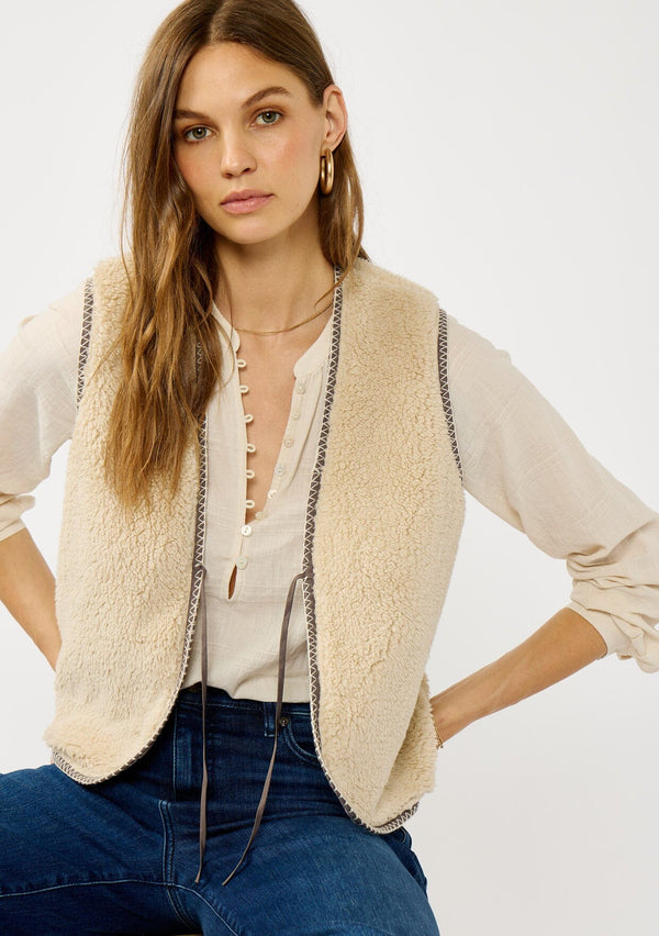 [Color: Natural/Lavender] A front facing image of a blonde model wearing a cozy fall natural sherpa vest with a tie front detail and side pockets. Perfect for layering any boho look. 