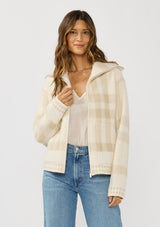 [Color: Ivory/Taupe] A front facing image of a brunette model wearing an ivory plaid jacket with a zip up front and side pockets. 
