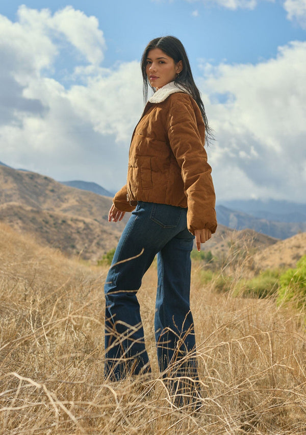 [Color: Camel] A side facing image of a brunette model outside wearing a brown corduroy puffer jacket with a sherpa collar, zip-up front, and welt pockets. A classic corduroy jacket for the fall season. 