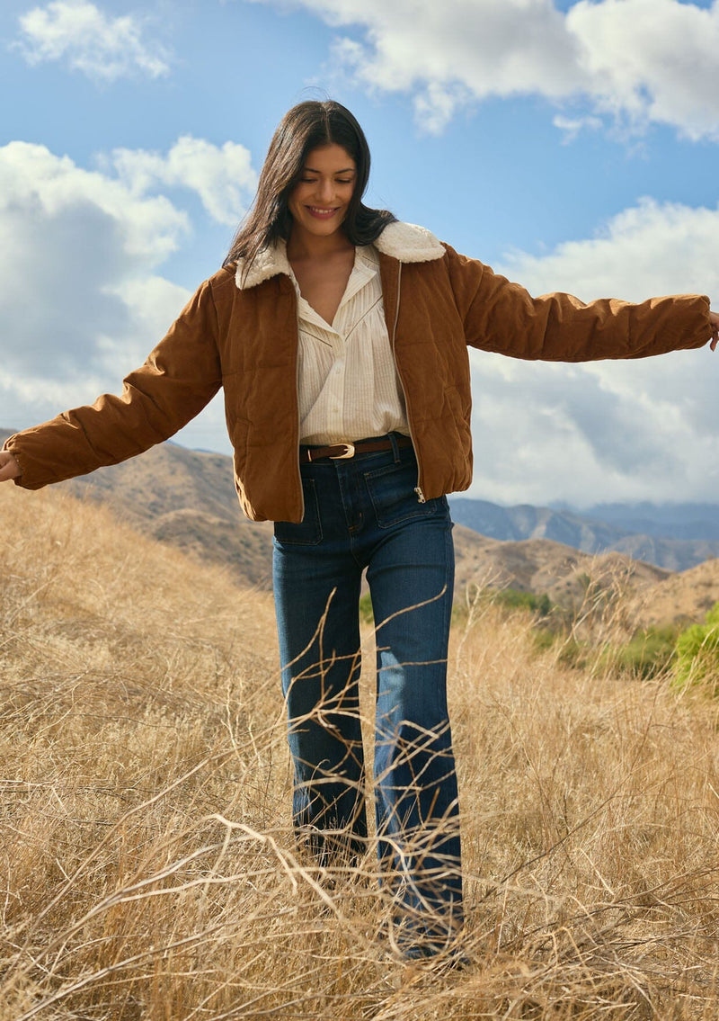 [Color: Camel] A front facing image of a brunette model outside wearing a brown corduroy puffer jacket with a sherpa collar, zip-up front, and welt pockets. A classic corduroy jacket for the fall season. 