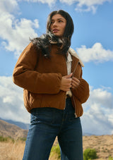[Color: Camel] A front facing image of a brunette model outside wearing a brown corduroy puffer jacket with a sherpa collar, zip-up front, and welt pockets. A classic corduroy jacket for the fall season. 
