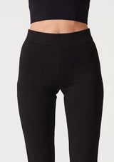 [Color: Black] A close up front facing image of a blonde model wearing a slim fit black flared legging designed in Ponte. With an elastic waist. 
