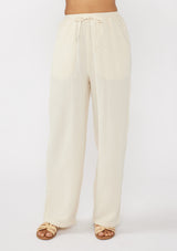 [Color: Tea Dye] A front facing image of a light beige pant crafted in cotton gauze with an elastic drawstring waistband, side pockets, and wide legs. Ideal for beach styling and lounging. 