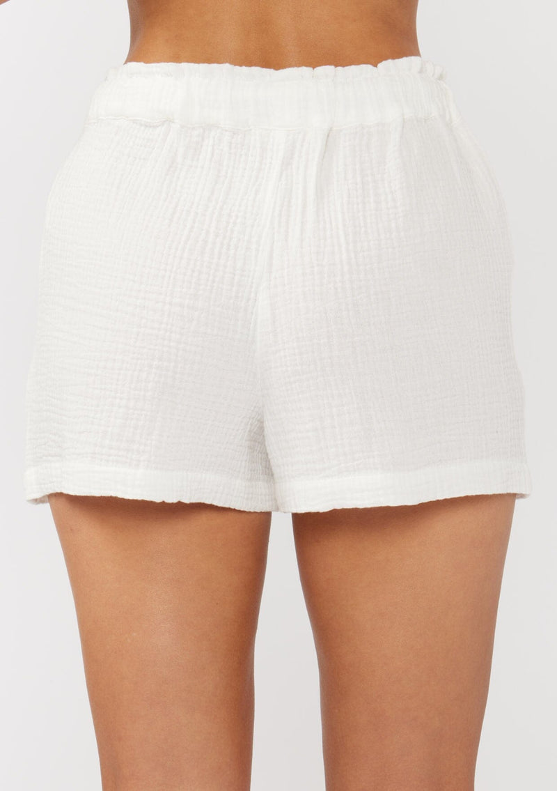 [Color: White] A back facing image of white cotton gauze shorts with an elastic drawstring waist and side pockets. Perfect for spring, lounging, or beach days. 
