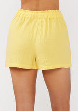 [Color: Yellow] A back facing image of yellow cotton gauze shorts with an elastic drawstring waist and side pockets. Perfect for spring, lounging, or beach days. 