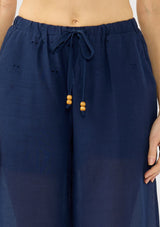 [Color: Navy] A detail image of a navy eyelet pant with a beaded drawstring and side pockets. 