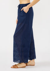 [Color: Navy] A side facing image of a navy eyelet pant with a beaded drawstring and side pockets. 