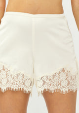 [Color: Champagne] A detail image of an off white satin lace short. 