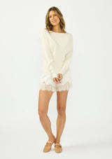 [Color: Champagne] A front facing image of an off white satin lace short. Paired with an off white pullover and nude ballet flats. 