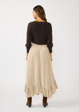 [Color: Taupe] A back facing image of a brunette model wearing a taupe maxi length skirt. With a trendy low rise waist, a ruffled hemline, smocked elastic waist details, and a flowy silhouette.