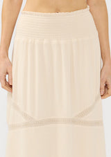 [Color: Natural] A detail image of a beige bohemian maxi skirt with a smocked waist and lace trims. 