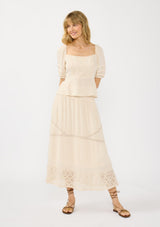 [Color: Natural] A front facing image of a beige bohemian maxi skirt with a smocked waist and lace trims. Styled with a matching short puff sleeve top.