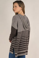 [Color: Cement/Dark Chocolate] An image of a blonde model wearing a grey and brown striped pullover hoodie with a contrast sleeve, drawstring, and kangaroo pockets. Casual and laid back for the fall season. 