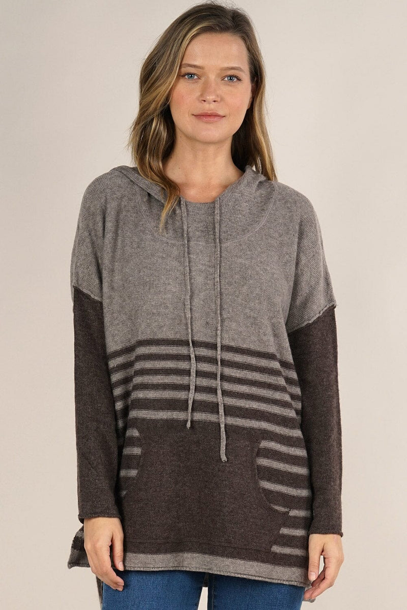 [Color: Cement/Dark Chocolate] An image of a blonde model wearing a grey and brown striped pullover hoodie with a contrast sleeve, drawstring, and kangaroo pockets. Casual and laid back for the fall season. 