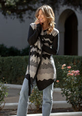 [Color: Black/Grey] A front facing image of a blonde model wearing an abstract cardigan with an adjustable waist belt. 