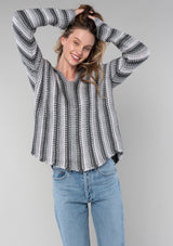 [Color: Smoke/Steel] A front facing image of a blonde model wearing a vertical striped knit pullover with a hoodie, relaxed v-neckline, and cozy long sleeves. A classic knit sweater for casual outings. 