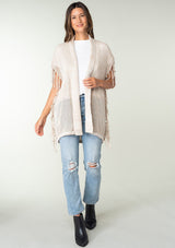 [Color: Bone] A front facing image of a brunette model wearing a open knit lightweight cardigan with fringe accents. An easy throw on for casual outings. 