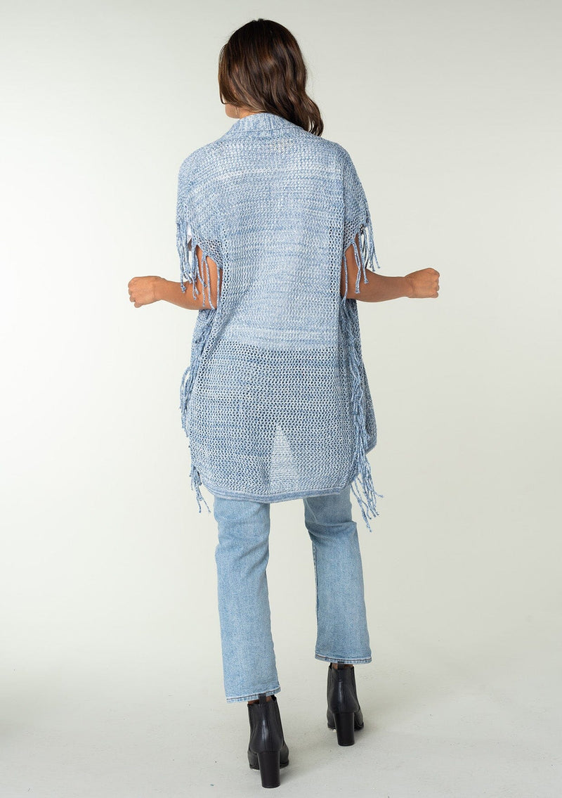 [Color: Chambray] A back facing image of a brunette model wearing a open knit lightweight cardigan with fringe accents. An easy throw on for casual outings. 