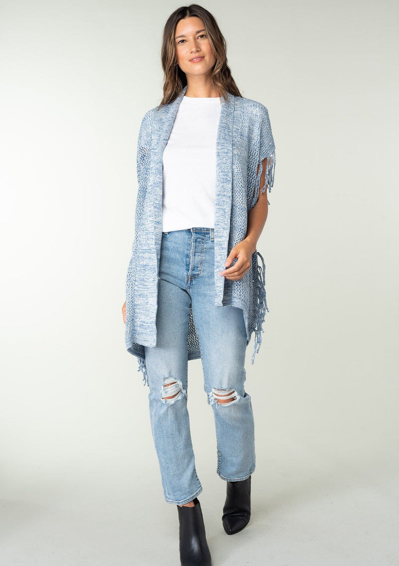 [Color: Chambray] A front facing image of a brunette model wearing a open knit lightweight cardigan with fringe accents. An easy throw on for casual outings. 