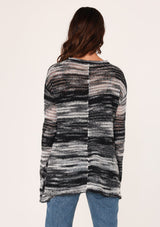 [Color: Black/Grey] A back facing image of a brunette model wearing a relaxed melange knit sweater. This lightweight sweater features a round neckline, a swing hem, and comfortable long sleeves with dropped shoulders. 