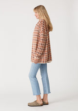 [Color: Rust/Natural] A side facing image of a blonde model wearing a fuzzy hooded cardigan in a brown plaid check design. With long sleeves and an open front.