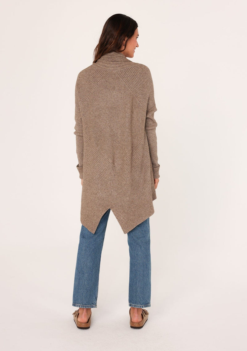 [Color: Mushroom] A back facing image of a brunette model wearing a brown shawl cardigan with a ribbed texture, open front, and a back vent detail. Cozy and relaxed for the fall season. 